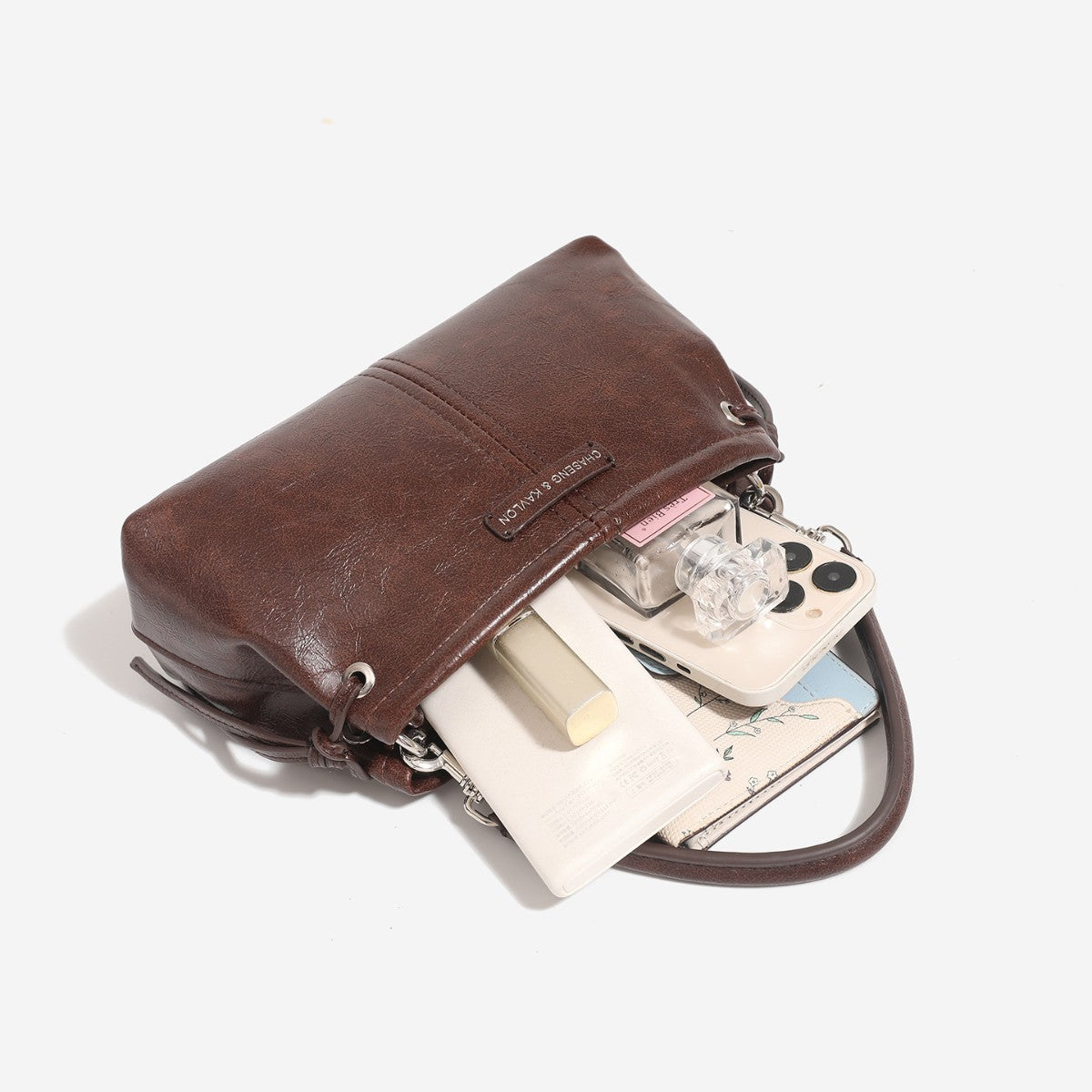 Small retro convertible shoulder bag with glossy leather-look finish, side drawstring ties, top zip closure, and silver-tone