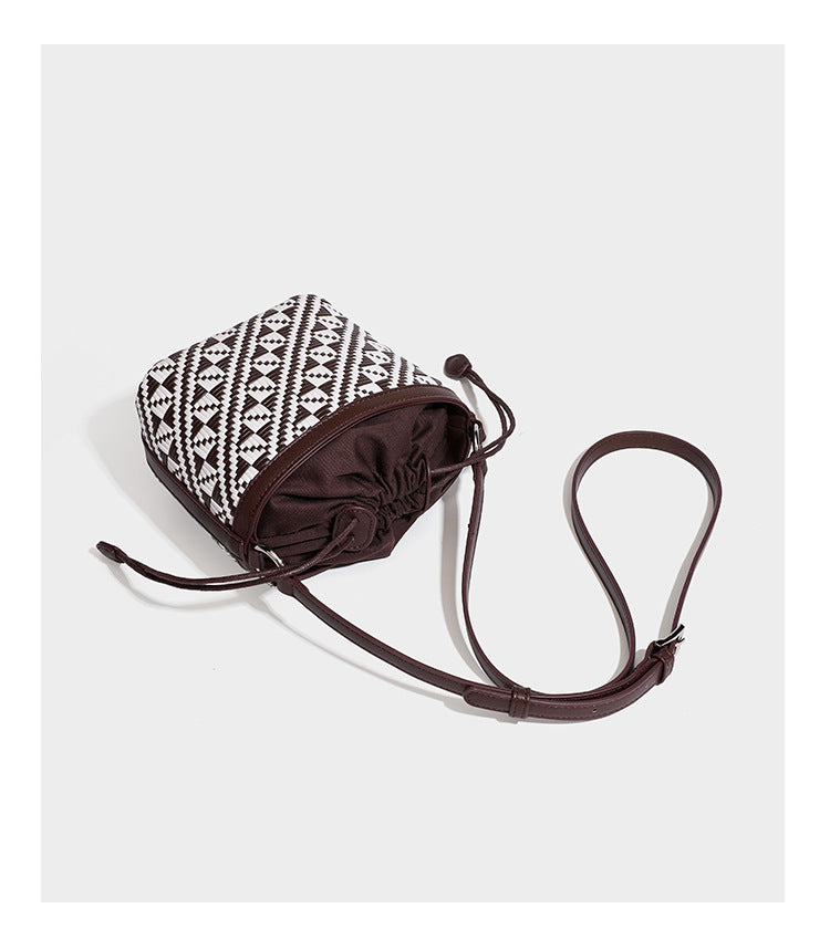 Kleine gewebte geometrische Bucket-Bag mit geflochtenem Henkel in Lederoptik und Kordelzugverschluss im zweifarbigen Muster aus Braun und Weiß