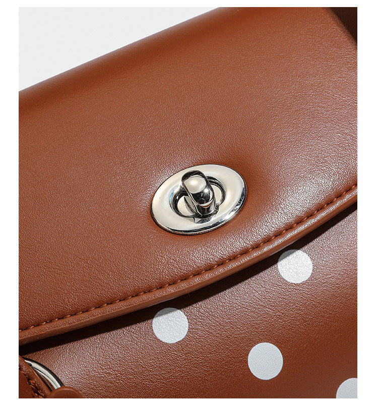 Strukturierte Baguette-Tasche mit Polka-Dot-Muster, glänzender Lederoptik, zwei Tragegriffen, silberfarbener Drehverschlussklappe und