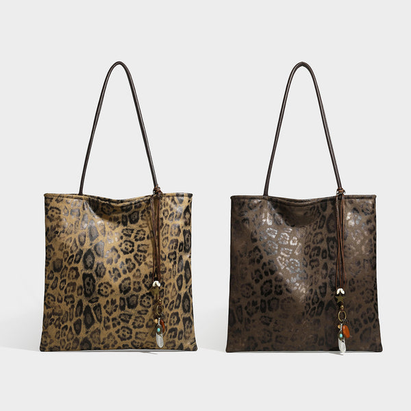Large leopard print shoulder tote bag in tan and brown with slim dark straps and dangling beaded charm hardware, detail view