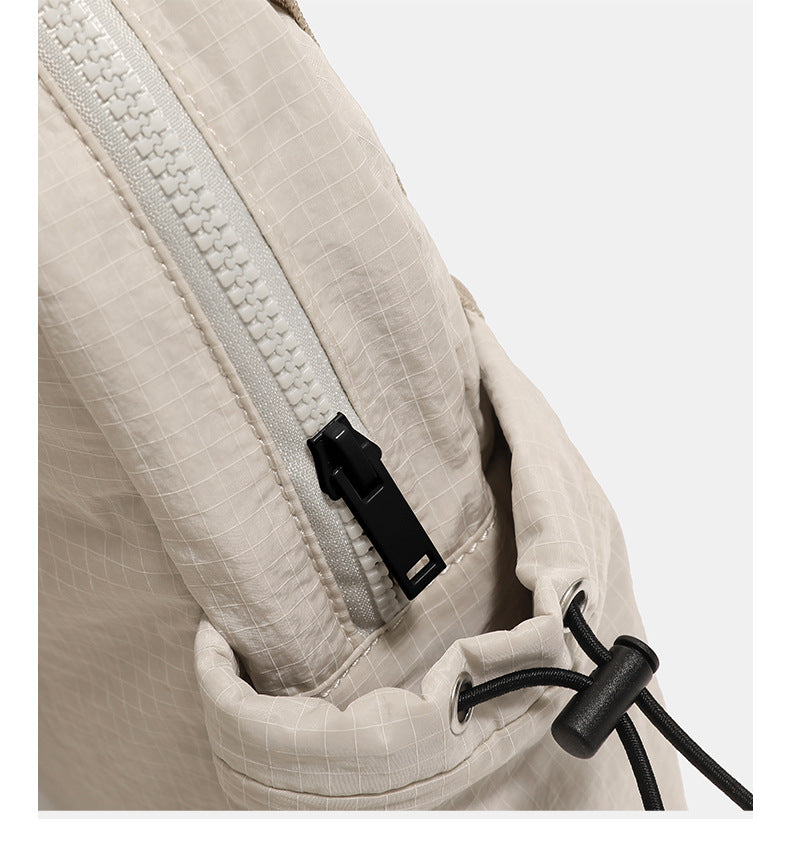 Small rounded mini backpack handbag in matte ripstop-texture fabric with top webbing handle, front pocket, side drawstring