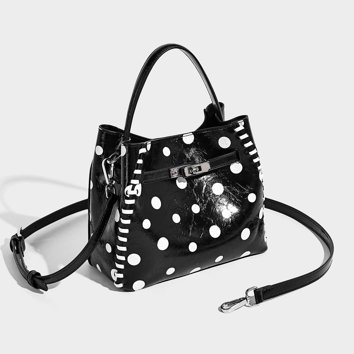 Glossy crinkled polka-dot bucket bag with silver-tone buckle hardware, contrast side lace trim, top handle, and detachable