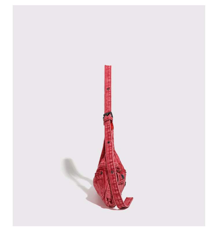Compact washed red distressed-textile shoulder bag with front flap pockets, dark metal hardware, and long adjustable strap