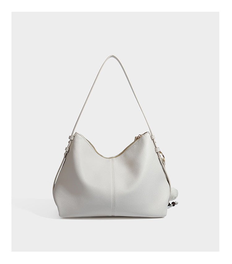 Slouchy hobo shoulder bag with pebbled leather-look finish, zip-top closure, gold-tone hardware, and hanging bead charm