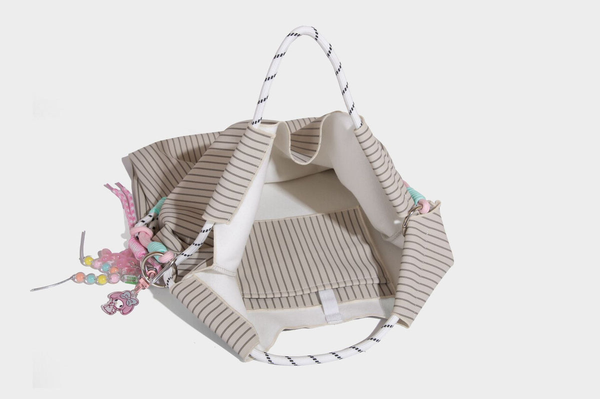 Slouchy pinstripe tote bag with braided rope handles, metal ring hardware, and colorful knotted rope charm, detail view 30