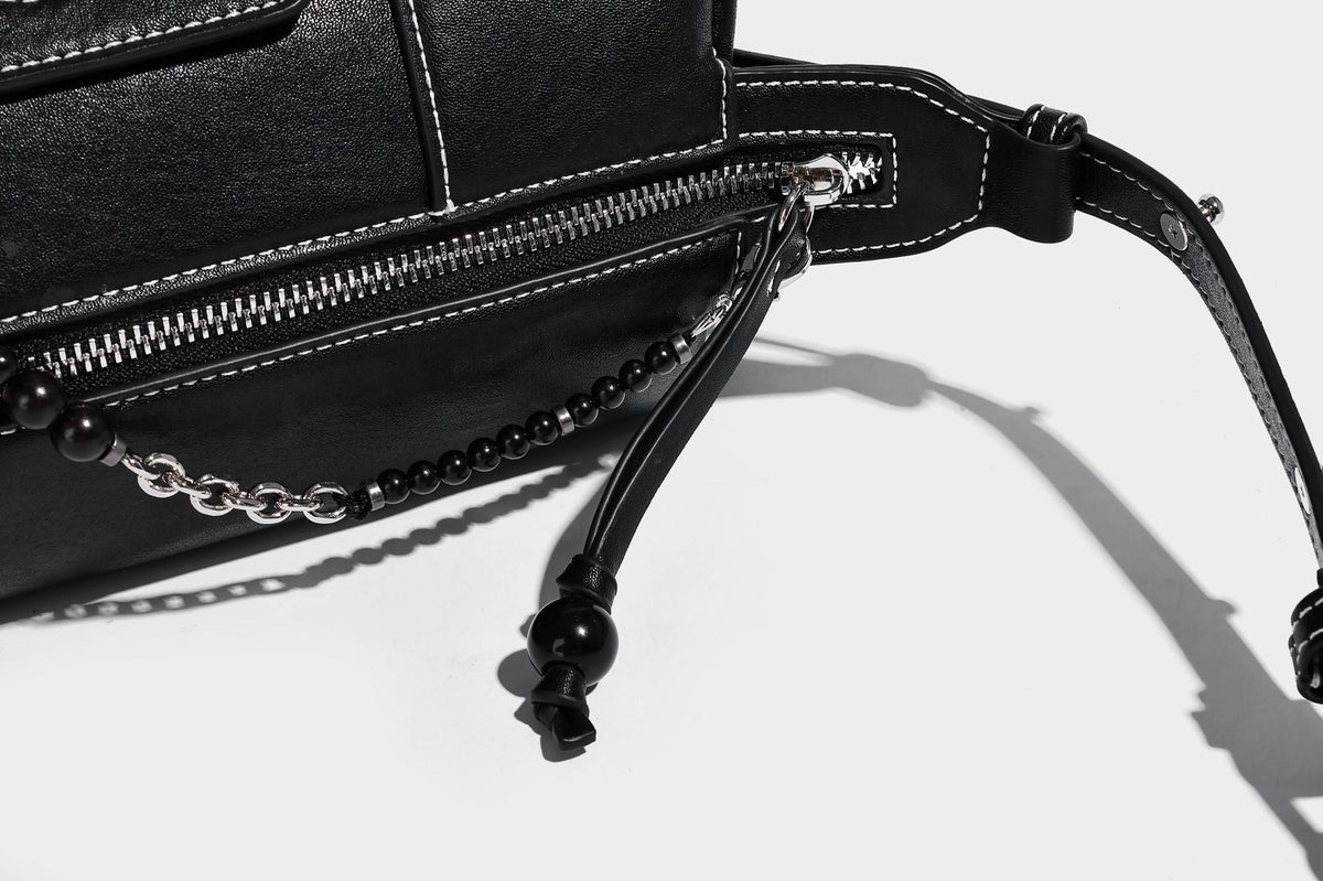 Small slouchy moto-style crossbody bag in smooth matte leather-look finish with white contrast stitching, silver-tone, detail