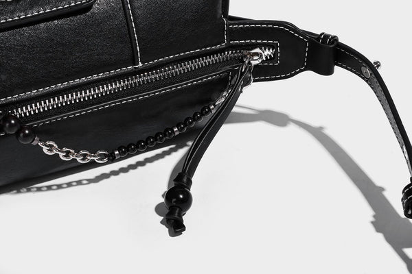 Small slouchy moto-style crossbody bag in smooth matte leather-look finish with white contrast stitching, silver-tone, detail