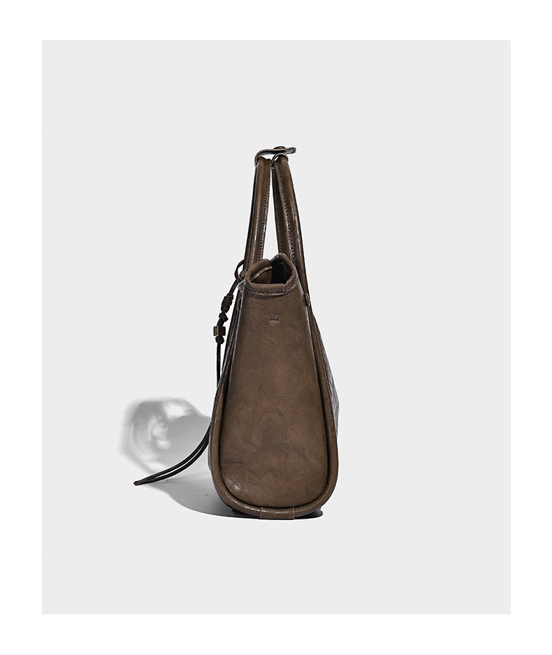 Glänzende Tote-Bag in geknautschter Lederoptik mit geprägtem rundem Emblem, Quastenschnürung, zwei Henkeln und abnehmbarem