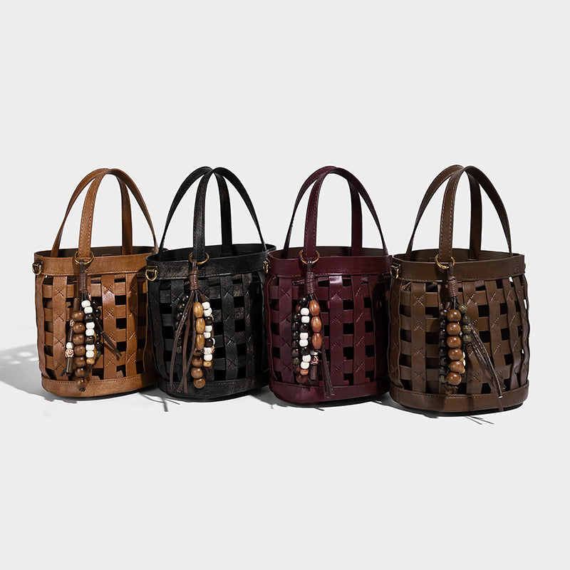 Small woven lattice bucket bag in brown leather-look finish with beaded tassel charm, dual top handles, and detachable