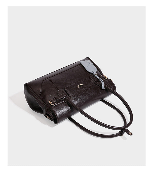 Structured glossy leather-look satchel bag with flap closure, gold-tone buckle accents, double top handles, detachable