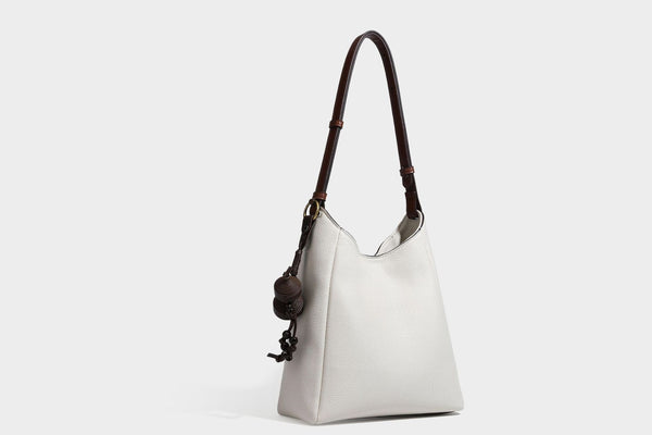 Hobo-Schultertasche in dunklem Espresso mit genarbter Oberfläche, warmen cognacfarbenen Details, verstellbarem schmalem Riemen, goldfarbenen Ringbeschlägen und geknotetem