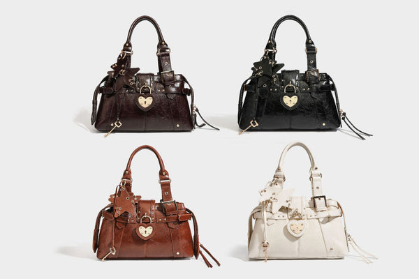 Structured leather-look satchel bag with heart padlock charm, star charm, gold-tone buckle hardware, dual top handles, and