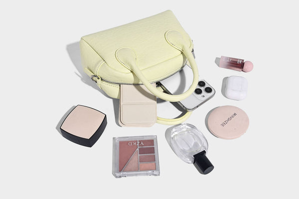 Mini-Tasche mit strukturierter Kuppelform und Tragegriff, in Pastellgelb mit genarbter Lederoptik, silberfarbenen Metallbeschlägen und abnehmbarem