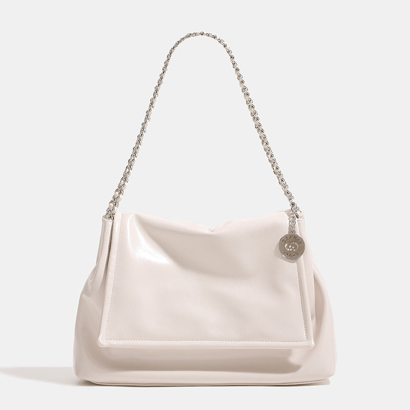 Soft trapezoidal chain-strap shoulder bag with foldover flap and circular logo medallion, detail view 7