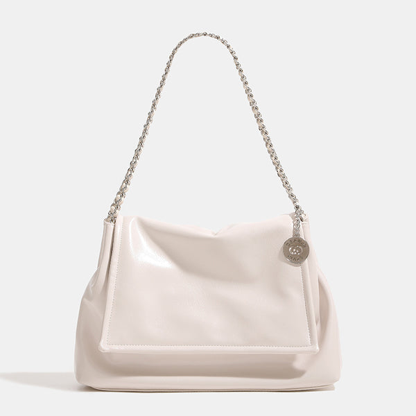 Soft trapezoidal chain-strap shoulder bag with foldover flap and circular logo medallion, detail view 7