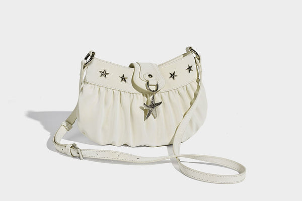 Ruched shoulder bag with curved flap, silver star studs, dangling starfish charm, and adjustable crossbody strap, detail view