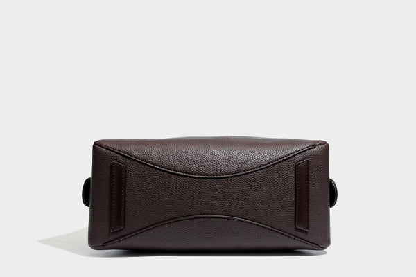 Structured trapezoid shoulder bag in dark brown pebbled leather-look finish with slim double straps, top zip closure, side
