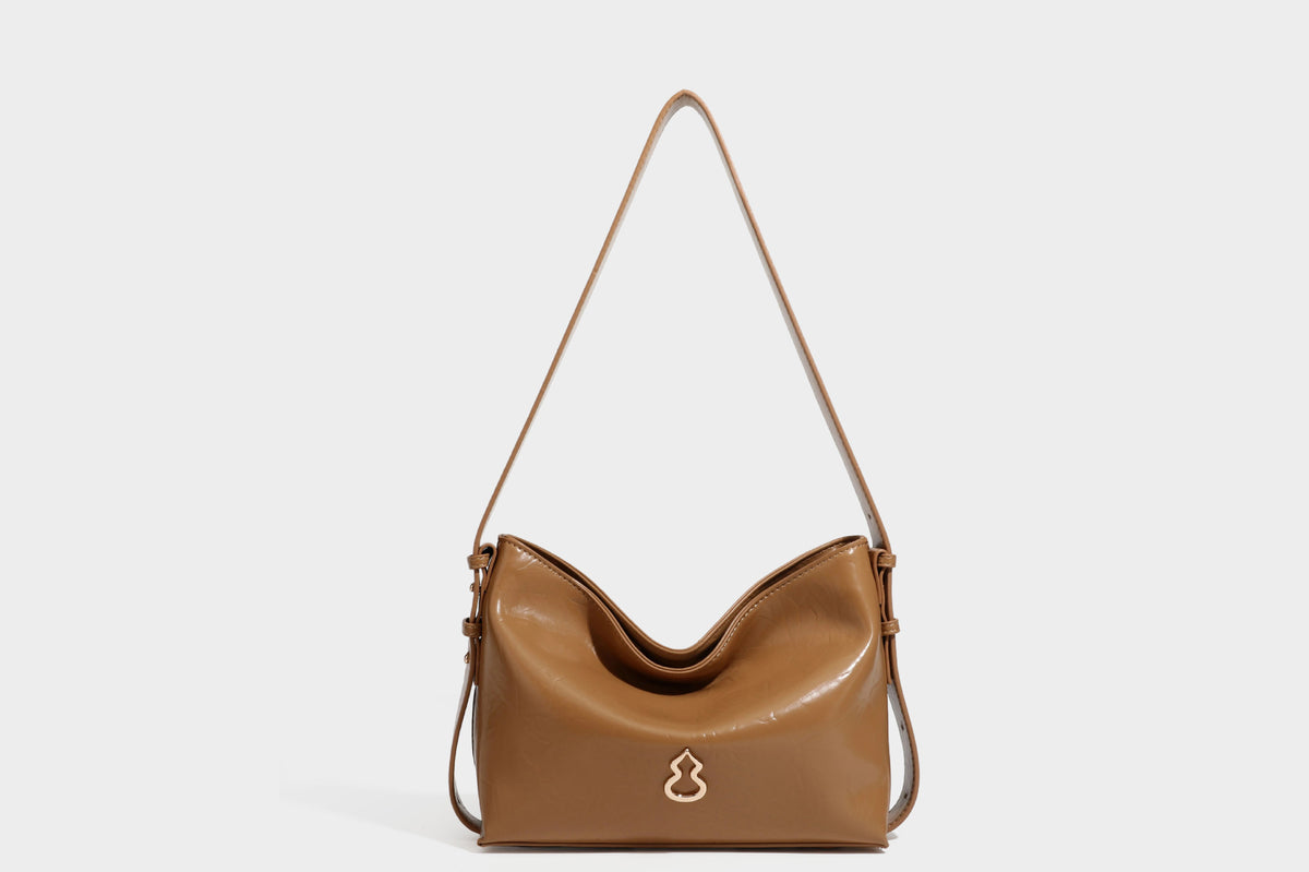 Lässige Hobo-Schultertasche mit offenem oberen Abschluss in glänzender karamellfarbener Lederoptik mit goldfarbenen Logo-Beschlägen und langem, verstellbarem