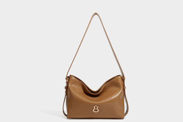 Lässige Hobo-Schultertasche mit offenem oberen Abschluss in glänzender karamellfarbener Lederoptik mit goldfarbenen Logo-Beschlägen und langem, verstellbarem
