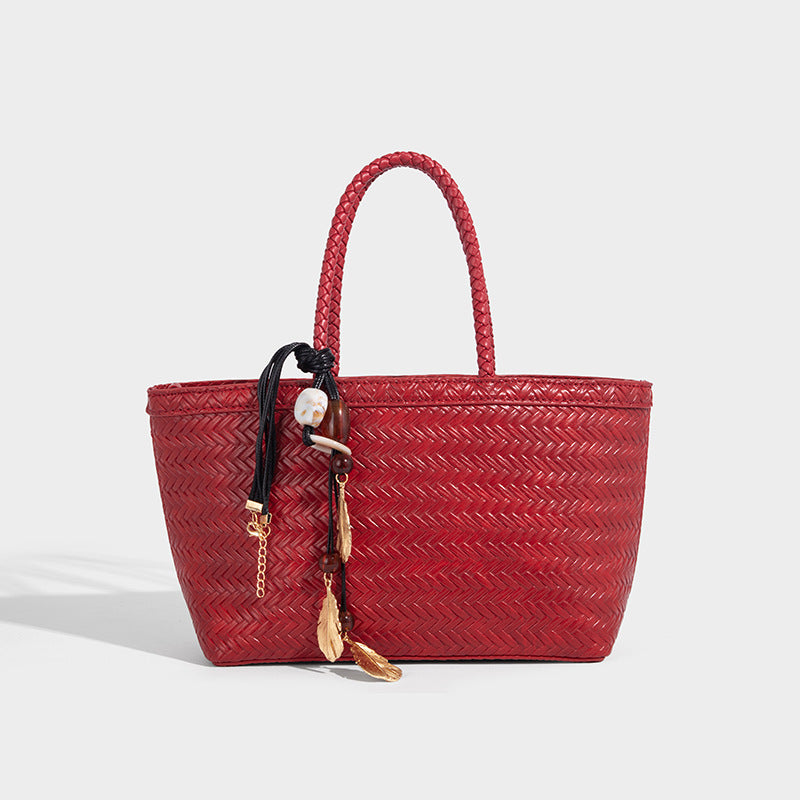 Structured chevron woven leather-look tote bag with braided top handles, gold feather charm, and adjustable shoulder strap
