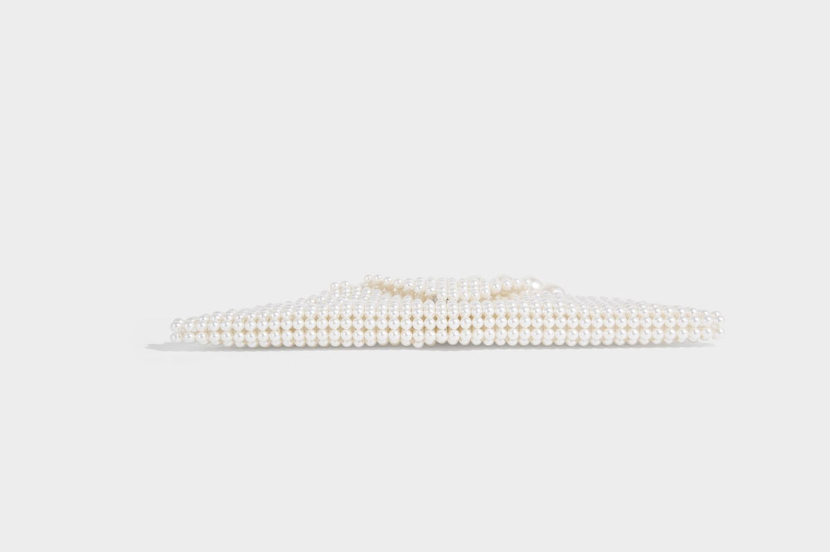 Small structured triangle clutch bag covered in glossy pearl beads with an arched pearl top handle and silver snap closure