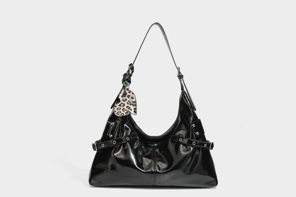 Glänzende dunkelbraune, lässig geschnittene Hobo-Schultertasche mit Riemendetail mit silberfarbenen Ösen, Reißverschlussfach auf der Vorderseite und Herz mit Leopardenmuster
