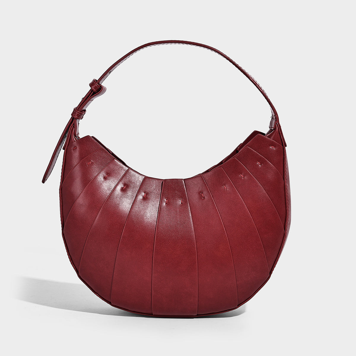 Crescent half-moon shoulder bag with vertical panel seaming, matte-satin leather-look finish, and adjustable gold-tone