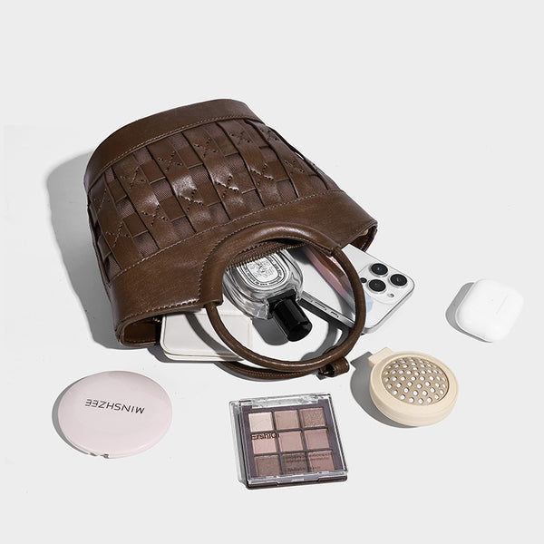 Small woven-panel bucket bag with circular ring handles, beaded tassel charm, and detachable crossbody strap in brown, detail