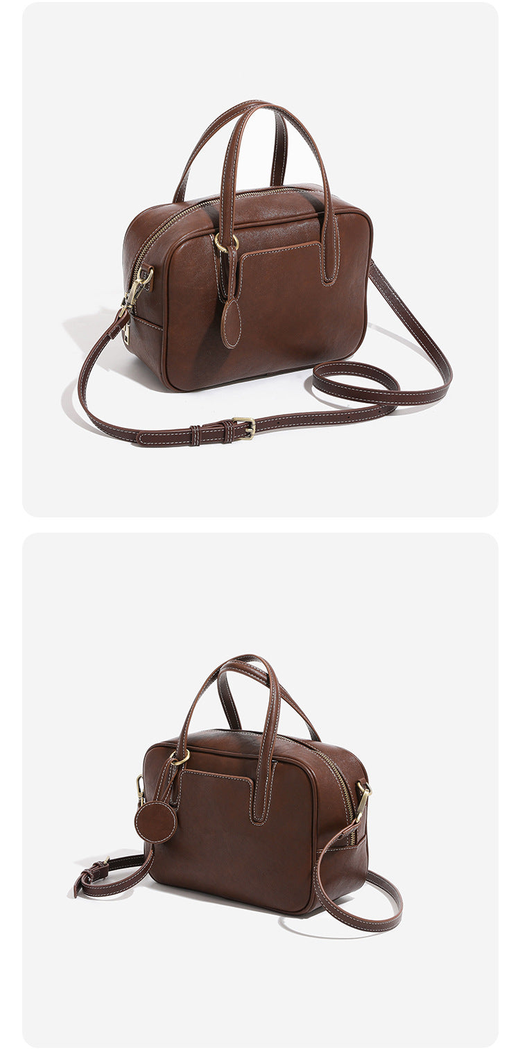 Structured boxy bowling-style tote bag in deep brown leather-look finish with dual top handles, front slip pocket, round