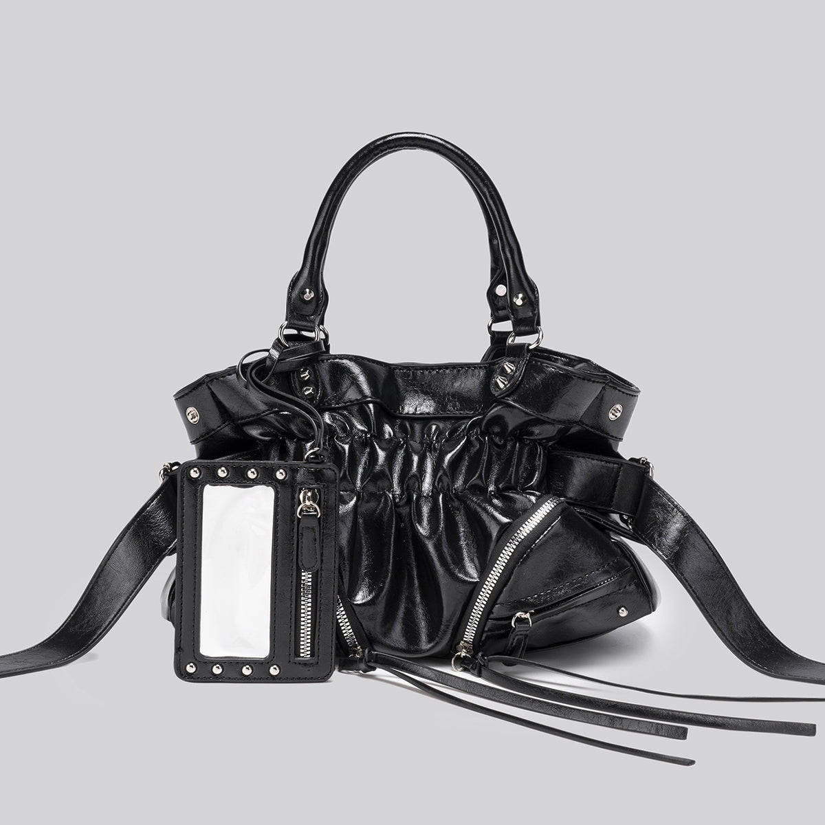 Black glossy ruched convertible tote bag with silver-tone rivets, detachable wide shoulder strap, external zip pouch, and