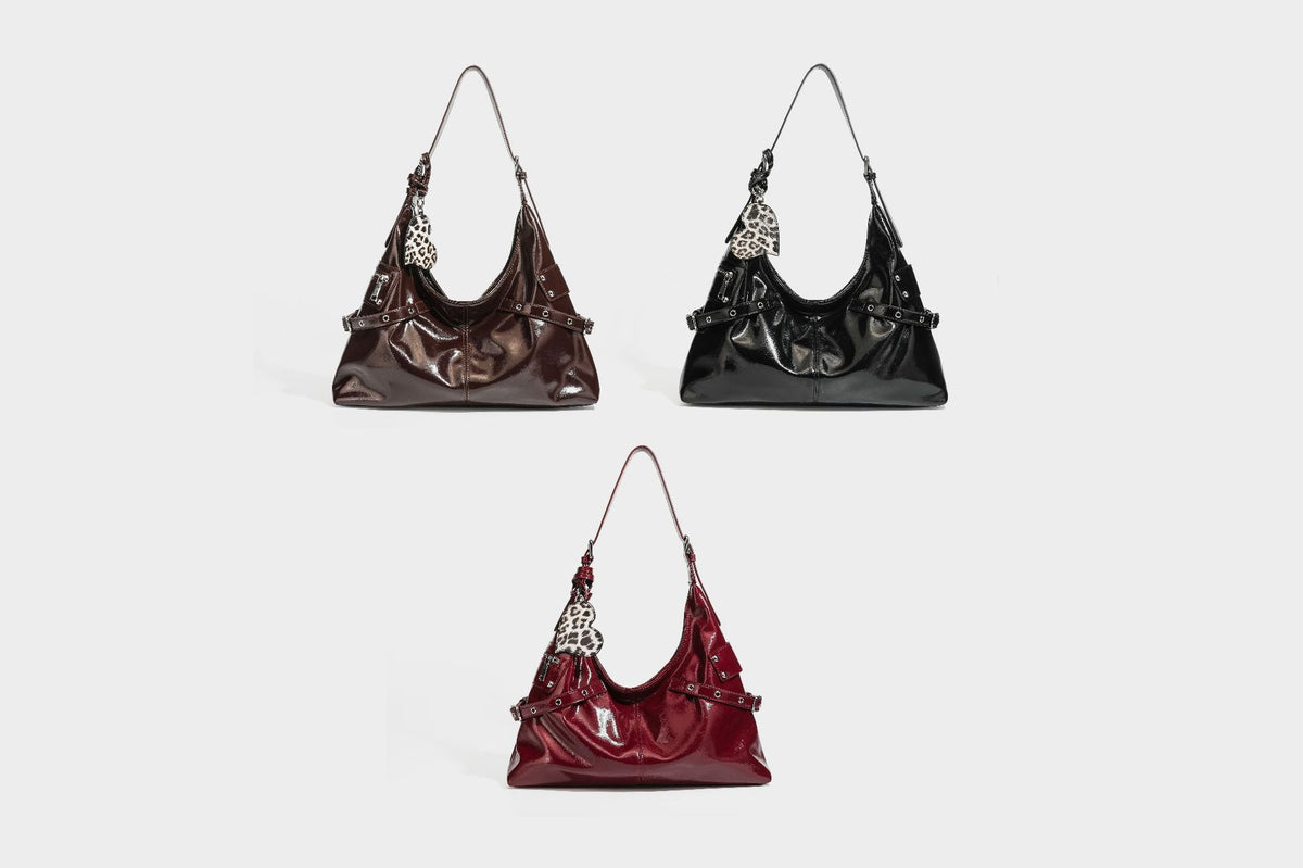Glänzende dunkelbraune, lässig geschnittene Hobo-Schultertasche mit Riemendetail mit silberfarbenen Ösen, Reißverschlussfach auf der Vorderseite und Herz mit Leopardenmuster