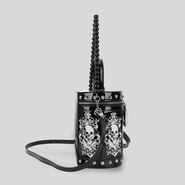 Black glossy cylindrical barrel bag with white skull-floral print panels, silver pyramid studs, black beaded top handle, and