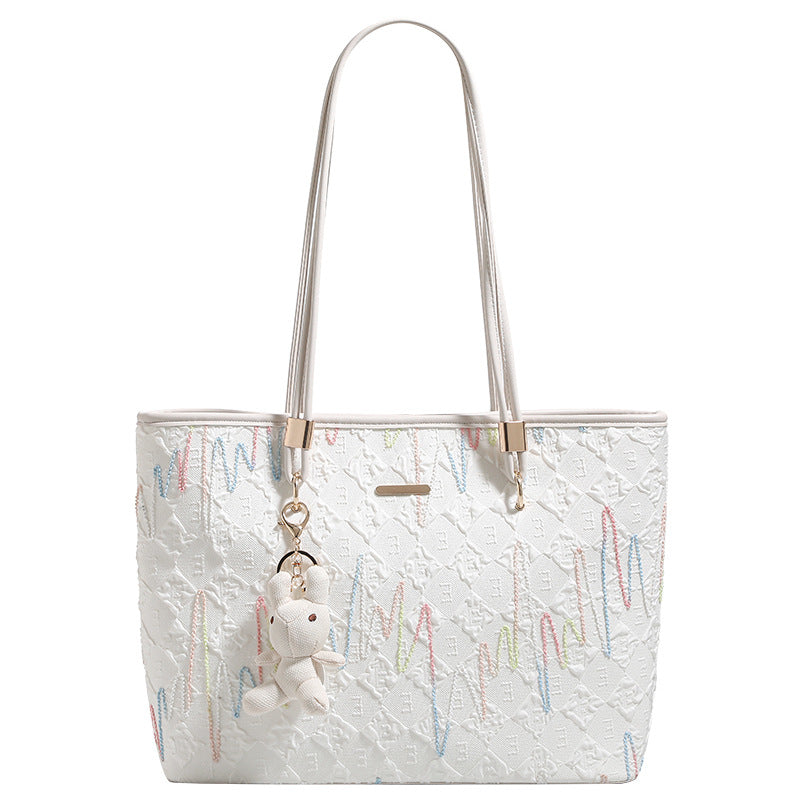 Off-white structured tote bag with dual shoulder straps, gold-tone hardware, and plush bear charm, detail view 5