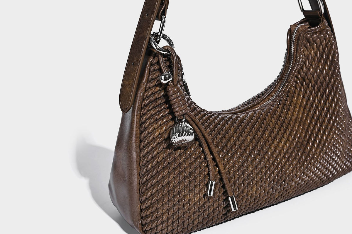 Woven crescent hobo shoulder bag with smooth side panels, zip-top closure, silver-tone charm hardware, and adjustable, detail
