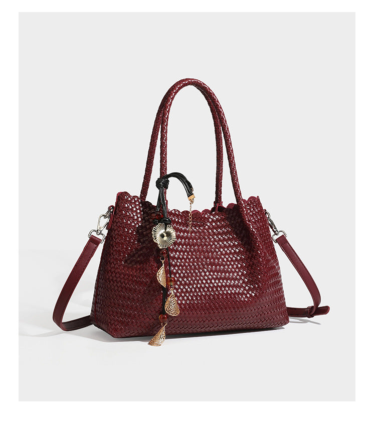 Strukturierter, glänzend geflochtener Shopper mit Muschelkantenabschluss am oberen Rand, geflochtenen Tragegriffen, abnehmbarem Crossbody-Riemen und Perlenquaste