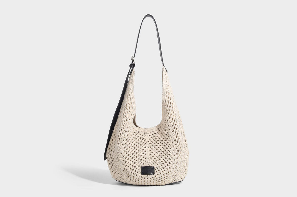 Cream openwork crochet hobo bag with black leather-look strap and trim patch accent, slouchy teardrop silhouette, detail view