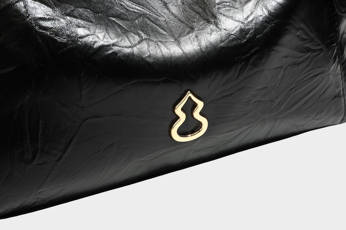 Große, glänzende Tote-Bag aus schwarzem Lederimitat mit geknitterter Optik, lässig fallender Trapezsilhouette, zwei Schulterriemen und goldfarbenen