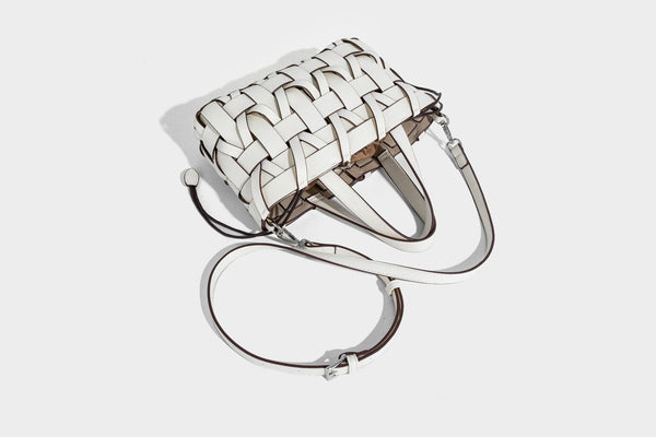 Structured woven basket tote handbag with contrasting dark trim, double top handles, detachable shoulder strap, and