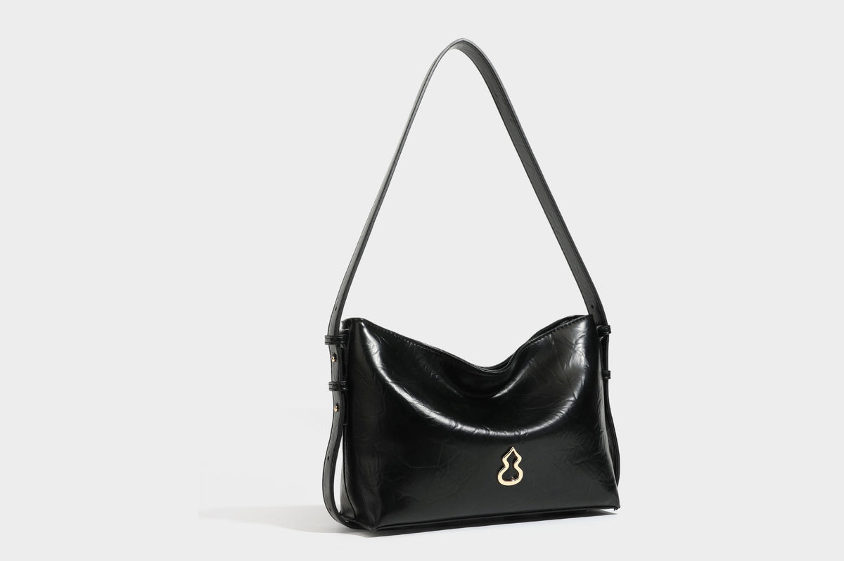 Lässig fallende Hobo-Schultertasche mit offenem Oberteil aus glänzender, karamellbrauner Lederoptik, mit Logo-Beschlägen in Goldoptik und langem, verstellbarem