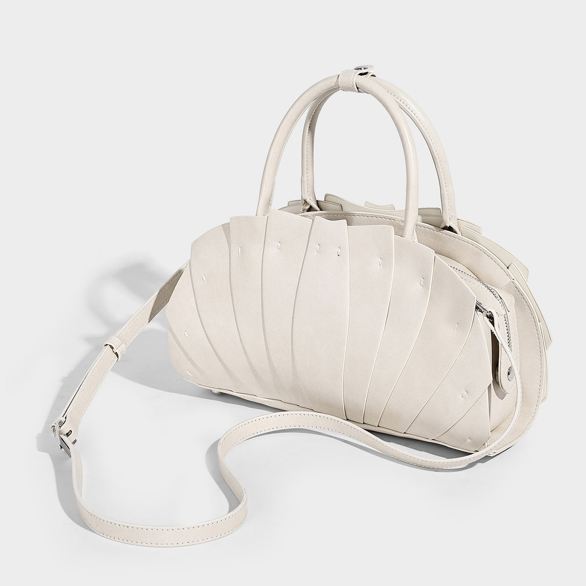 Structured dome satchel with fan-pleated leather-look exterior, dual top handles, and detachable shoulder strap, detail view