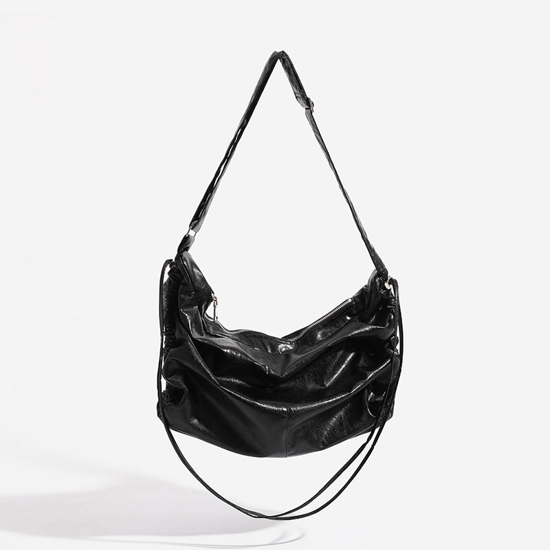 Oversized slouchy hobo shoulder bag with glossy crinkled leather-look finish, drawstring gathered sides, and silver-tone