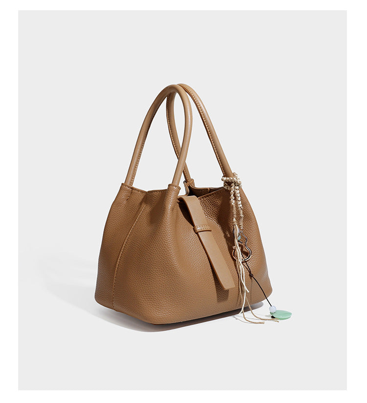 Pebbled leather-look bucket tote bag with rolled double handles, drawstring closure, braided cord charm, and detachable