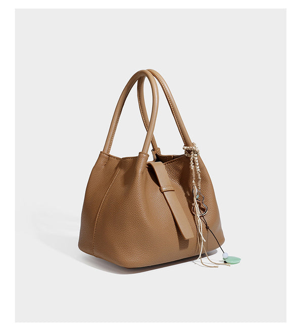 Pebbled leather-look bucket tote bag with rolled double handles, drawstring closure, braided cord charm, and detachable