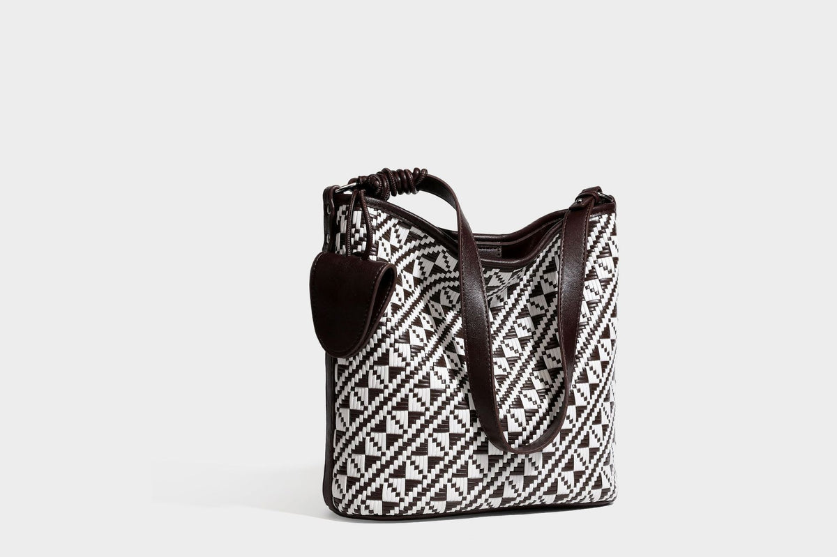 Geflochtene Schultertasche mit geometrischem Ethno-Muster, Besatz in dunkelbrauner Lederoptik, langem verstellbarem Träger und kleinem hängendem Reißverschluss