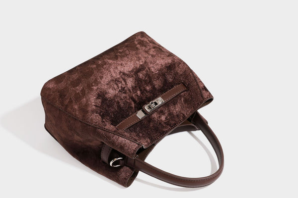 Small structured bucket satchel in embossed velvet-texture fabric with silver turn-lock hardware, rounded top handle, and