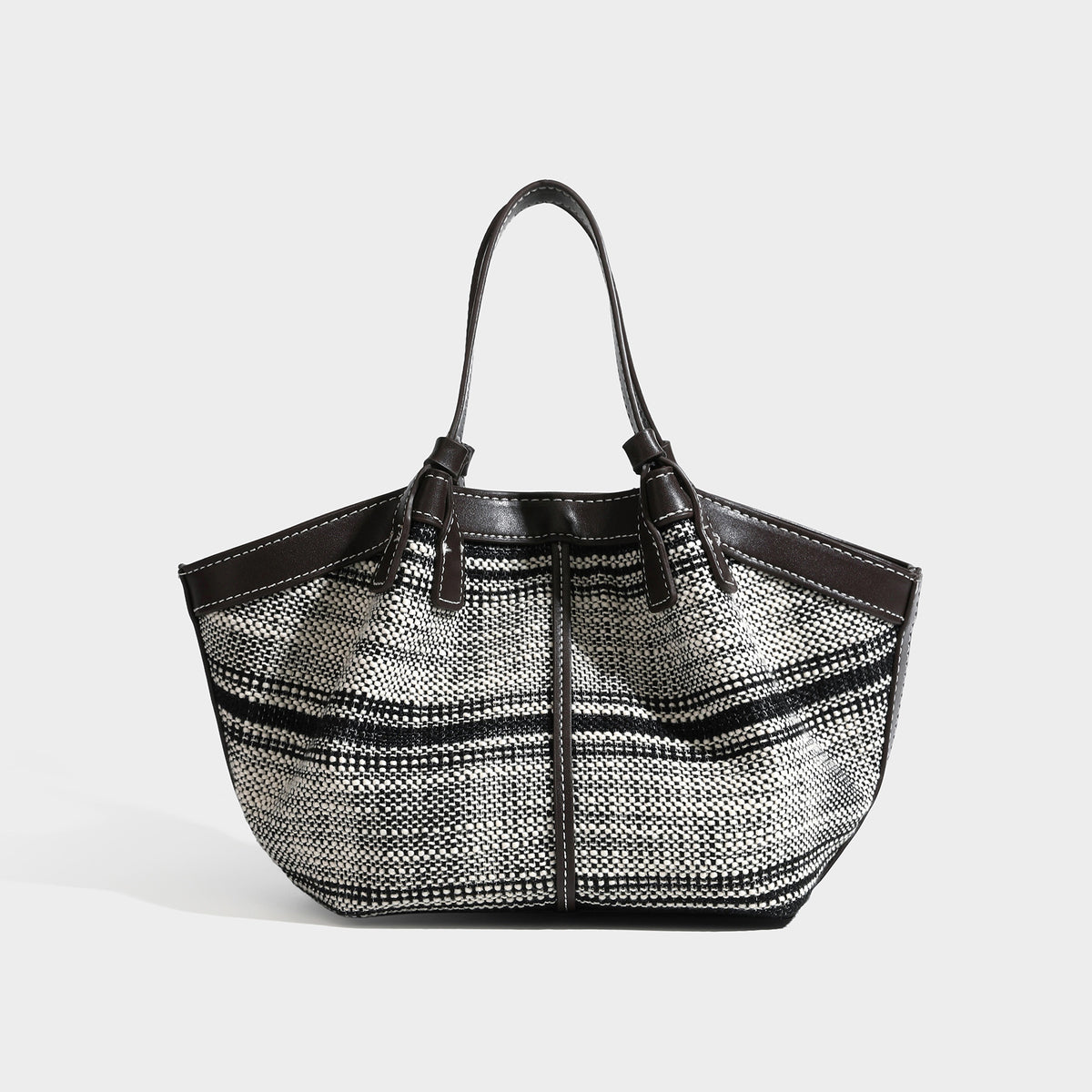 Schwarz-weiße gewebte Trapez-Tote-Bag mit dunklem Lederimitat-Besatz, weißen Kontrastnähten und zwei Henkeln, Detailansicht