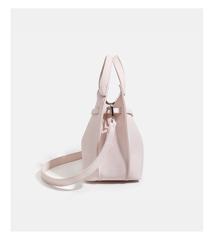 Compact pebbled leather-look shoulder bag with crossed silver-toned metal front closure, short top handle, and long, detail
