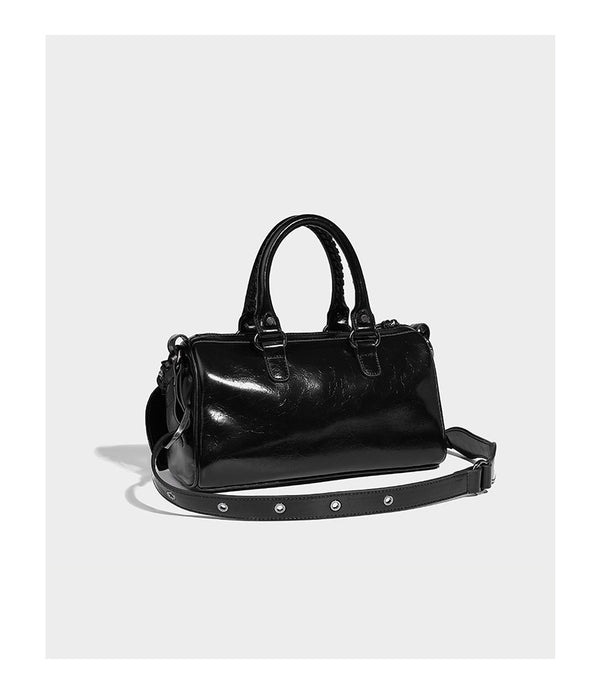 Glossy studded mini satchel bag with braided top handles, front zip pocket, heart charm, and detachable crossbody strap
