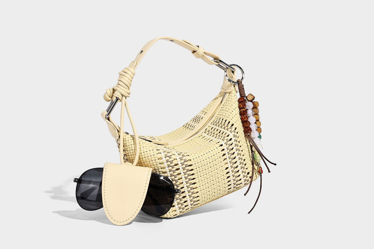 Small woven crescent shoulder bag with leather-look trim, zip closure, silver-tone ring hardware, and beaded tassel charm