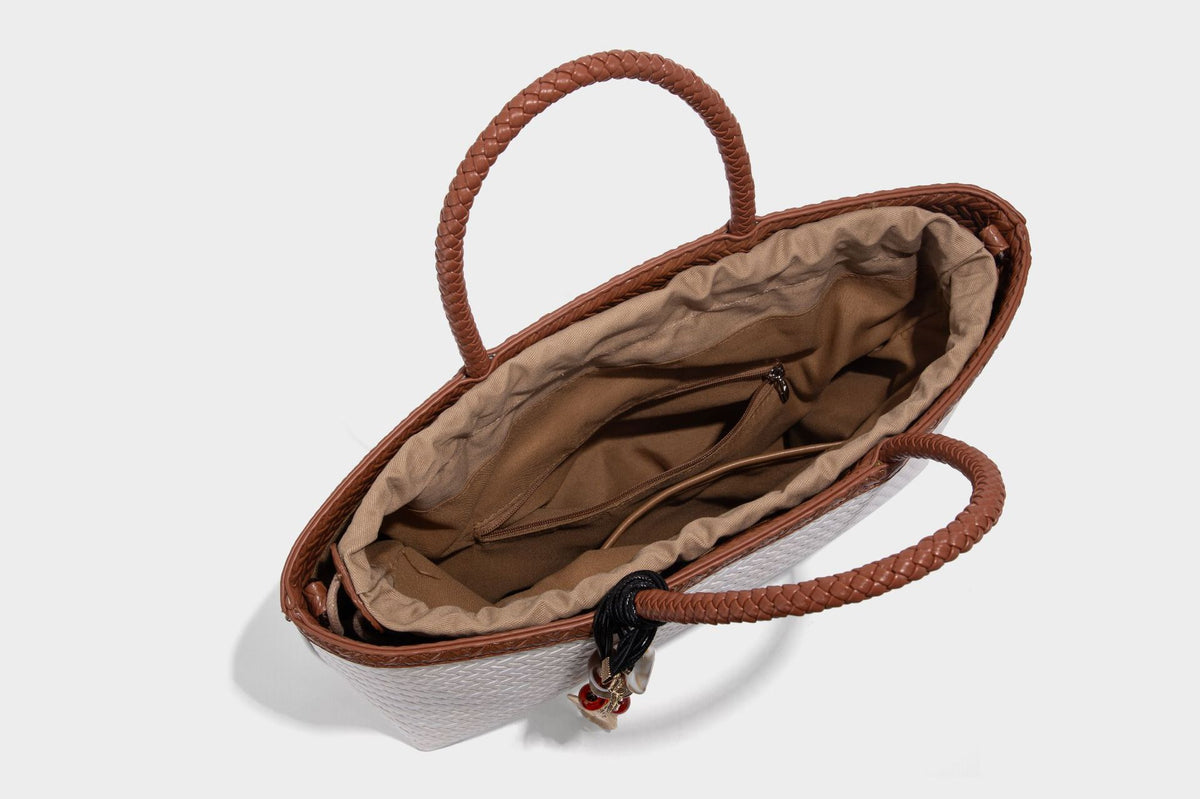Structured woven-texture tote bag with brown braided top handles, decorative tassel charm, and detachable shoulder strap